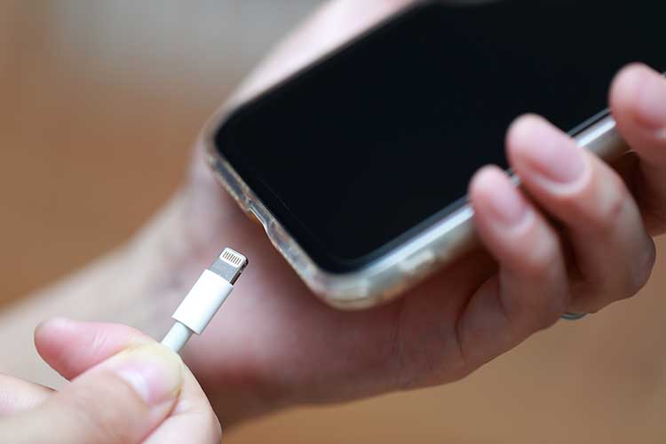 スマートフォンを持ち充電ケーブルを挿そうとする様子