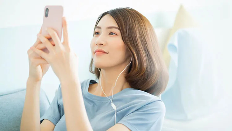 イヤホンをしてiPhoneを見る女性